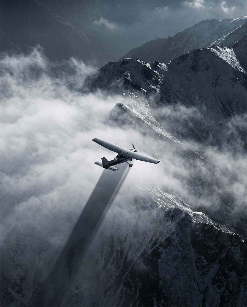 Survey aircraft flying through cloud over mountains